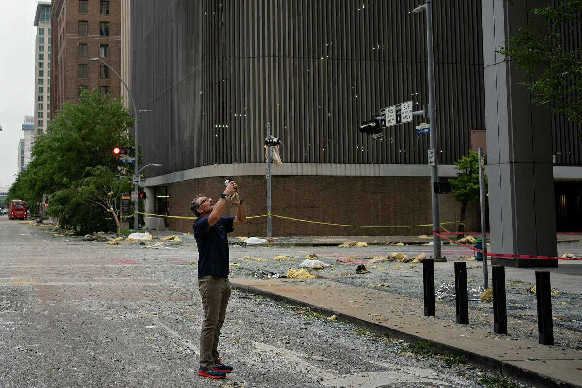 Martin Blinn, visiting Houston from Austin where his house also flooded, takes pictures of damage in downtown Houston, Texas on May 17, 2024.