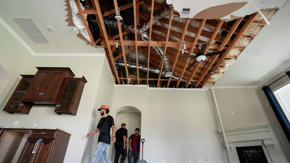 A restoration crew work in a home while cleaning up storm damage on Sunday, May 19, 2024, in Cypress. The suburban Houston area of Bridgeland suffered major damage last week after a line of powerful storms, that included a confirmed tornado, swept through the area.