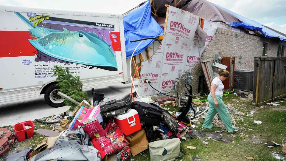 A woman named Olga, who declined to give her last name, walk around her heavily damaged home as her family begin the process of cleaning up storm damage on Sunday, May 19, 2024, in Cypress. The suburban Houston area of Bridgeland suffered major damage last week after a line of powerful storms, that included a confirmed tornado, swept through the area.