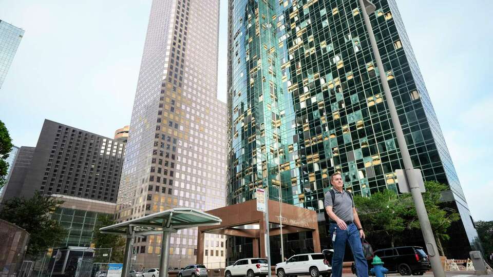 Pedestrians walk past buildings with broken windows downtown as they return to work on Monday, May 20, 2024 in Houston. The city closed off streets in a six-block exclusion zone downtown, from McKinney to Polk and from Smith to Travis, as workers continued to clean up broken glass from downtown streets and windows.