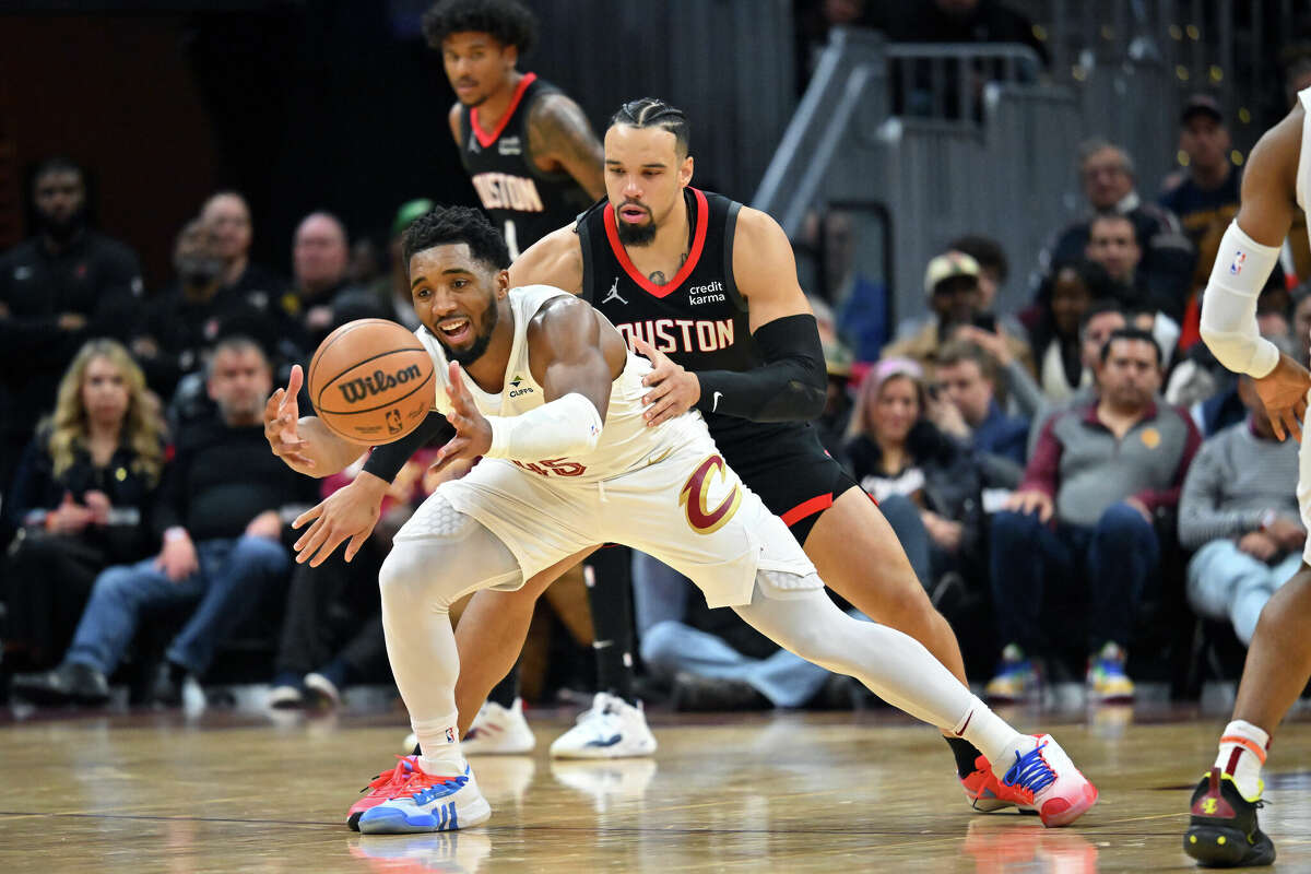 Donovan Mitchell #45 of the Cleveland Cavaliers grabs a loose ball while under pressure from Dillon Brooks #9 of the Houston Rockets during the fourth quarter at Rocket Mortgage Fieldhouse on December 18, 2023 in Cleveland, Ohio.