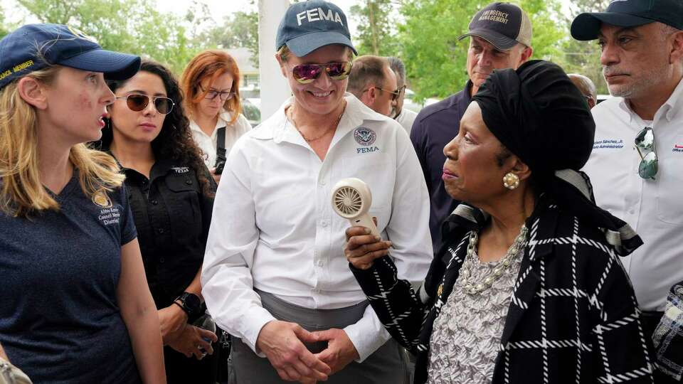 U.S. Congresswoman Sheila Jackson Lee, from right, FEMA Administrator Deanne Criswell and Harris County Judge Lina Hidalgo pass a small fan among each other to cool down in the heat while they visit Sinclair Elementary School Tuesday, May 21, 2024 at Timbergrove in Houston.