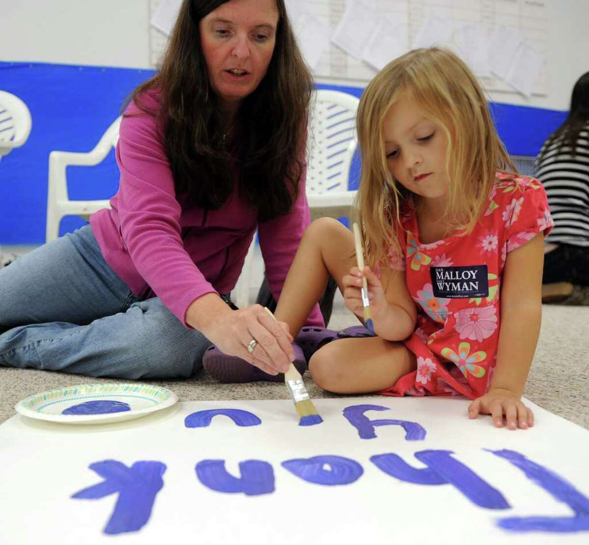 Katie Freimuth, 4, right, and her mother Maureen Driscoll, left, paint a sign for President Obama at Jim Himes' campaign office in Fairfield on Thursday, October 28, 2010.