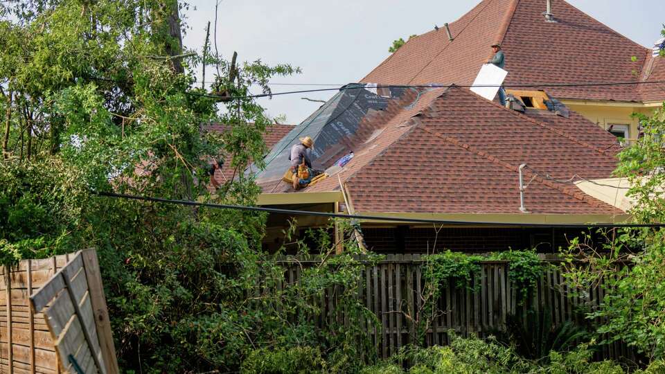 Workers repair a roof in northeast Houston, TX on Tuesday May 21, 2024. The area sustained extensive damage and loss of power due to fallen trees and high winds caused by the powerful storms that swept through the Houston region last Thursday.