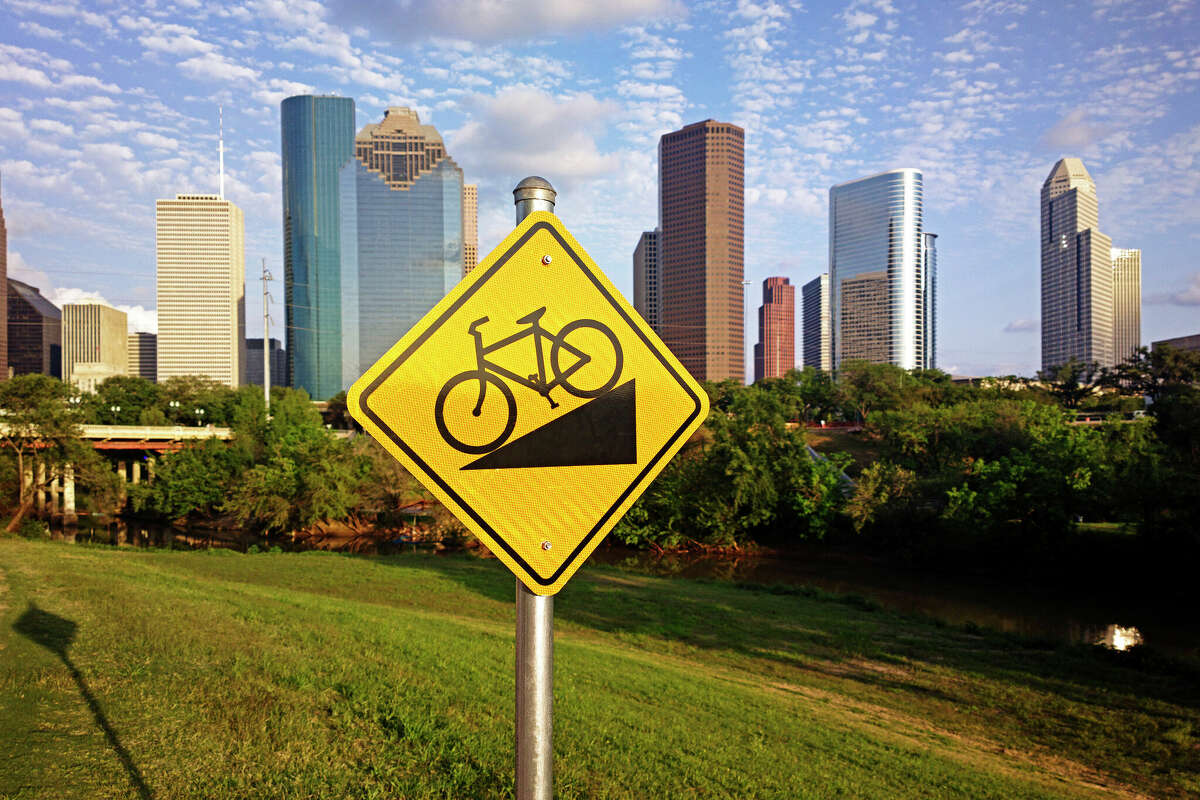 Bike trail sign on the foreground and view of skyscrapers from downtown Houston, Texas in the background.