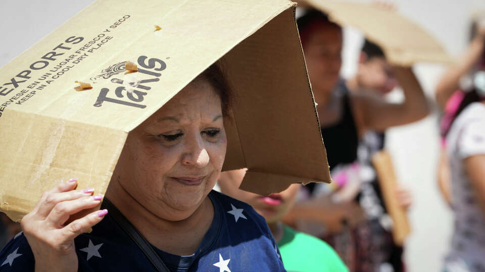 Margaret Cantu waits in the heat to get food and water from volunteers last Saturday at Sam Houston Math, Science and Technology Center in Houston. Heat index values this weekend will surpass 100 degrees.