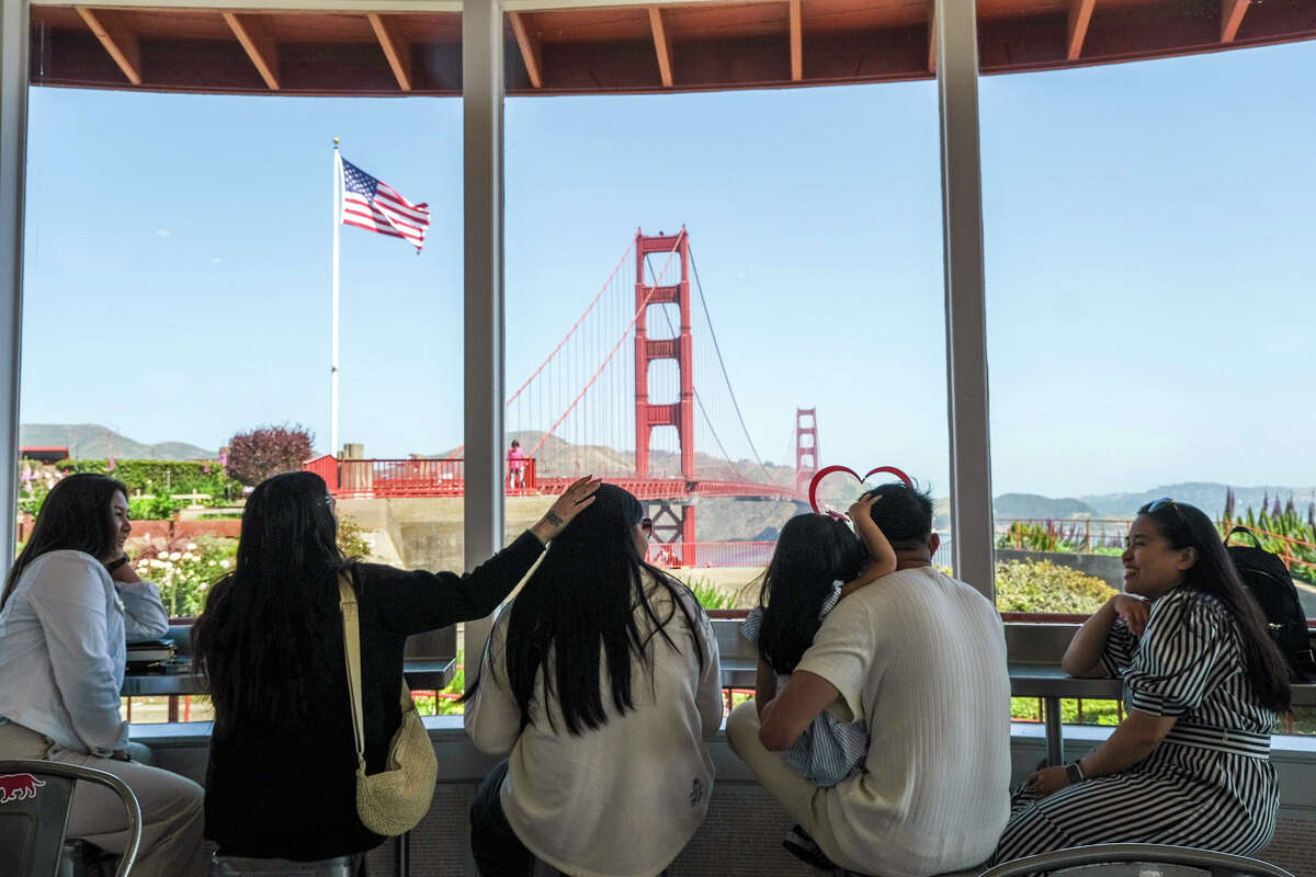 The Tullao family, visiting from Toronto, Canada, enjoy Equator Coffee at The Roundhouse Cafe and the view of the Golden Gate Bridge, on Wednesday, May 22, 2024.