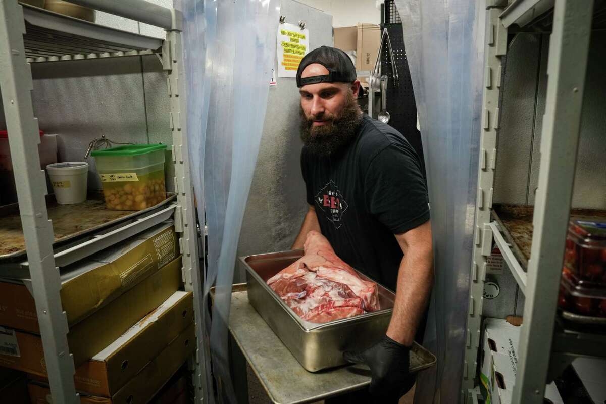 Zach Cook loads meet into a cooler in the aftermath of destructive storms Thursday, May 23, 2024, at Feges BBQ in Houston. The restaurant's owner Patrick Feges said they had just had power restored the day before, and that food was delivered that morning.