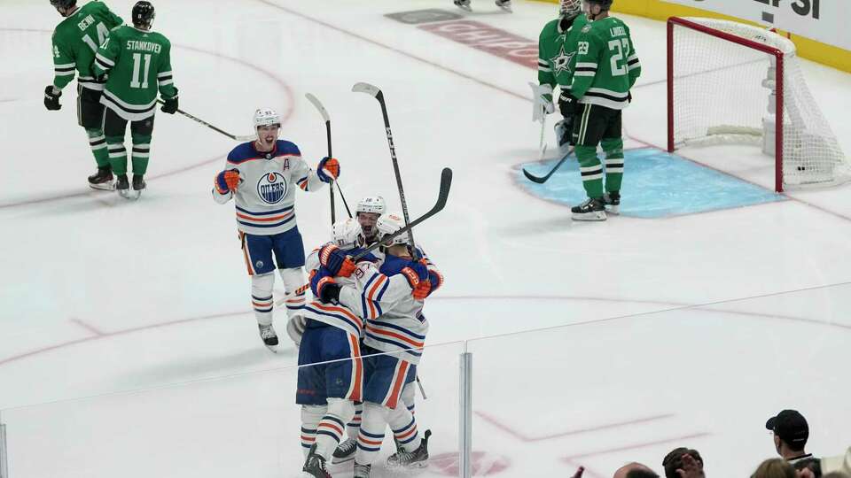 Edmonton Oilers players celebrate a game-winning goal by center Connor McDavid, bottom, left, during the second overtime in Game 1 of the NHL hockey Western Conference Stanley Cup playoff finals against the Dallas Stars, Thursday, May 23, 2024, in Dallas.
