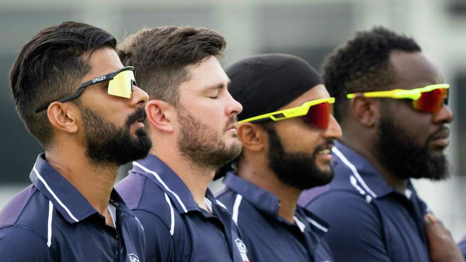 USA bowler Ali Khan, left, is seen alongside teammates during the national anthem before the third of a three-game T20I series at the Prairie View Cricket Complex, Saturday, May 25, 2024, in Houston.