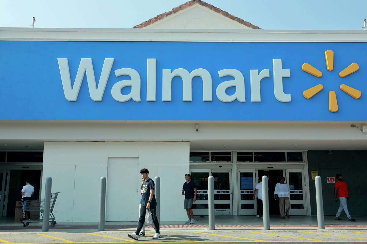 People walk near the entrance to a Walmart store on May 14, 2024 in Miami, Florida. Walmart announced that it will eliminate several hundred corporate jobs and relocate most of its remaining remote office staff. 