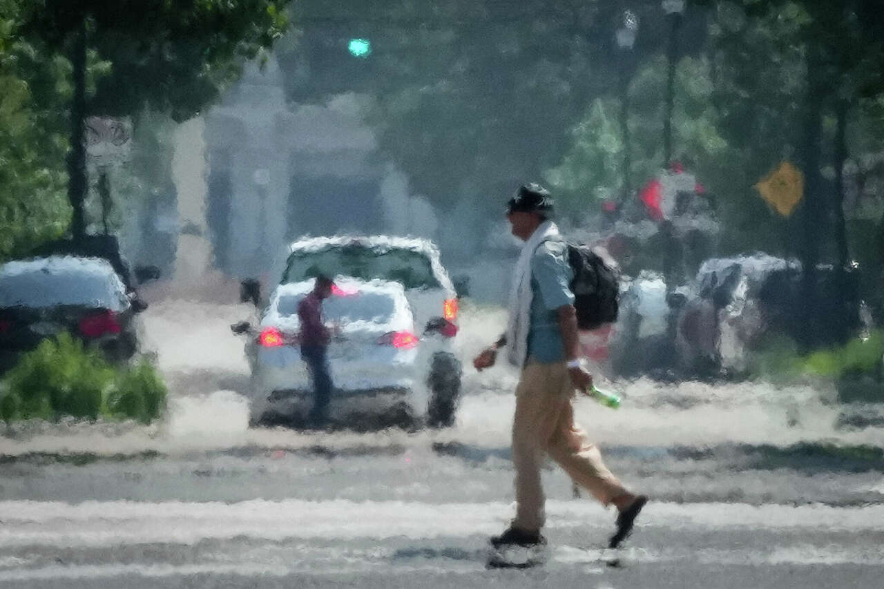 A person crosses Caroline Street in the afternoon heat on Saturday near Discovery Green in downtown Houston.