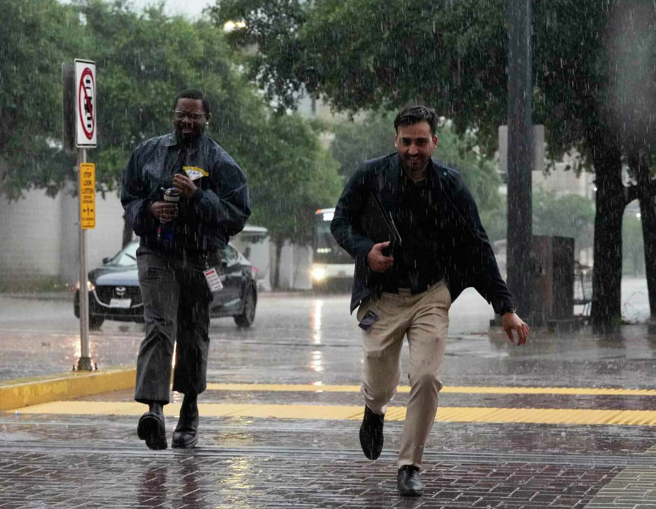 People brave the rain to cross Main Street at St. Joseph Parkway during the storm Tuesday, May 28, 2024 at in downtown Houston.