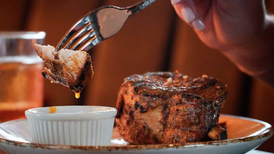 A restaurant worker models with a pork chop Wednesday, May 29, 2024, at Haywire in Houston.