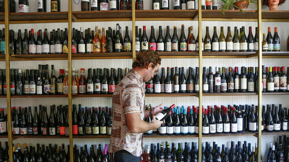 Light Years co-owner Steve Buechner looks through some of his stock in his hybrid wine shop-wine bar Tuesday, Oct. 6, 2020, in Houston.