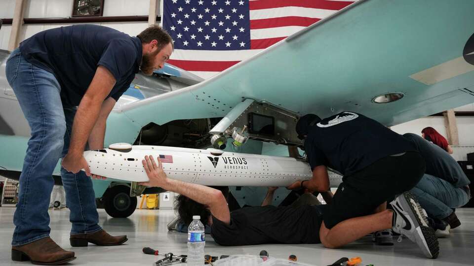 A team from Venus Aerospace loads a drone onto the wing of a training jet before an event with Sen. Ted Cruz, R-Texas, and Rep. Brian Babin, R-Texas, on Friday, May 31, 2024, at Venus Aerospace in Houston.