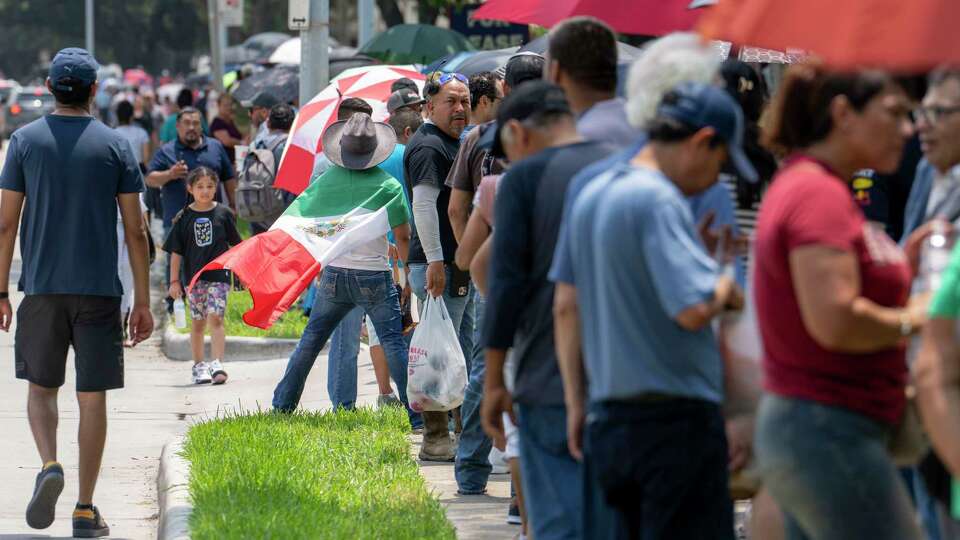 Max Aleman wears a Mexican flag to show his suport as he waits in a line that stretches multiple blocks down Richmond Avenue from the Mexican Consulate building Sunday, May 2, 2024.