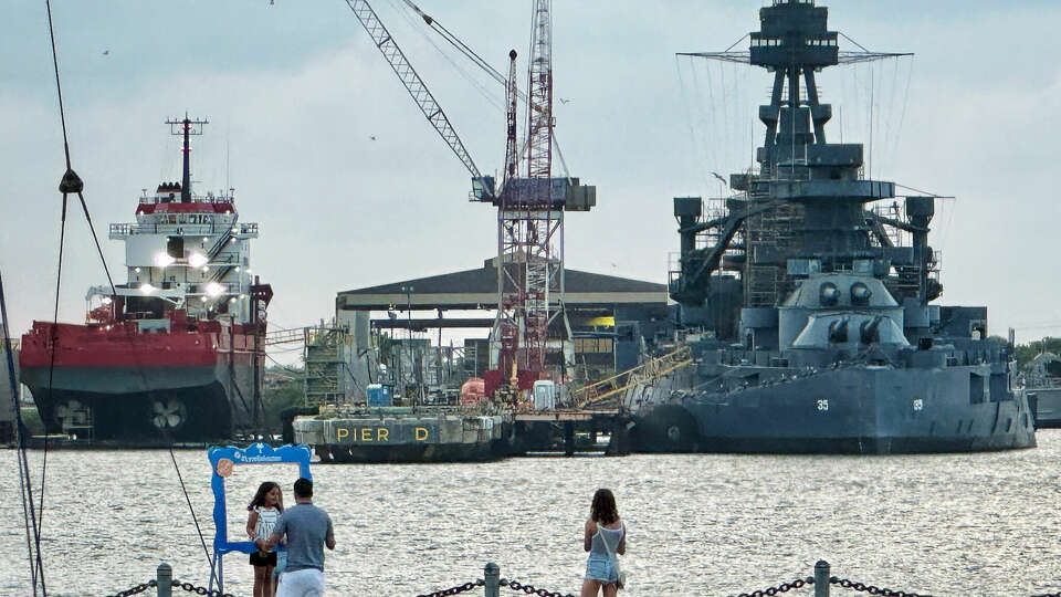 People take photos on Pier 21 with the Battleship Texas in the background on Saturday, May 24th, 2024 in Galveston, TX.