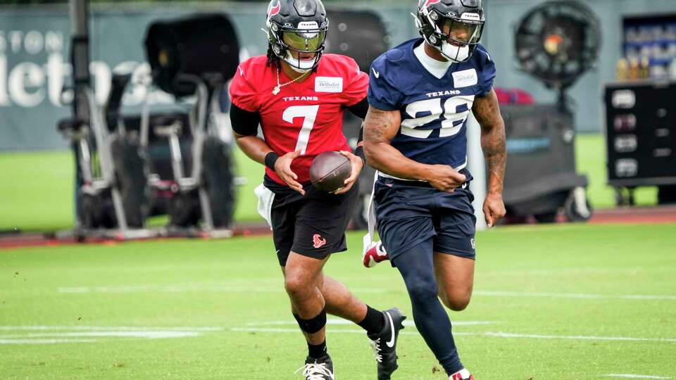 Houston Texans quarterback C.J. Stroud rolls out to pass as he runs a drill with running back Joe Mixon (28) during an NFL football mini camp practice on Tuesday, May 21, 2024, at Houston Methodist Training Center in Houston.