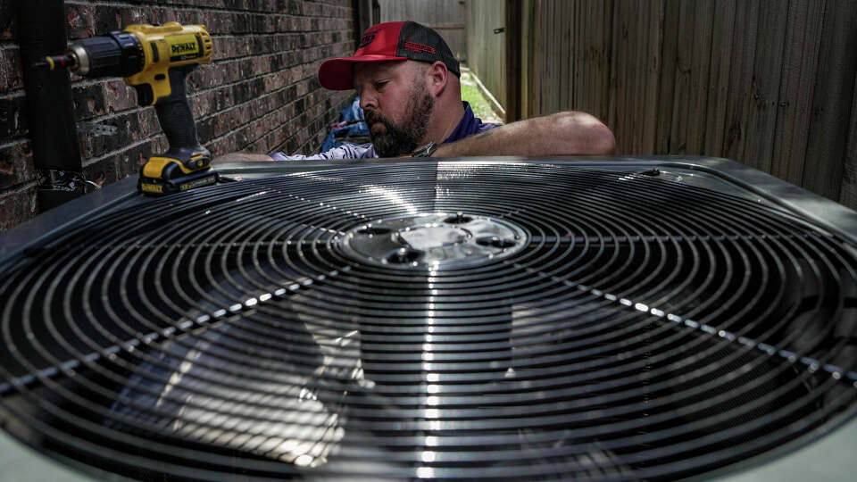 Ed Newby, owner of All Star A/C and Heating, works on an air conditioning unit on June 26, 2023, in Houston. Rising nighttime temperatures likely means A/C units working longer into the night to keep homes cool. That higher energy consumption can lead to higher electricity bills.