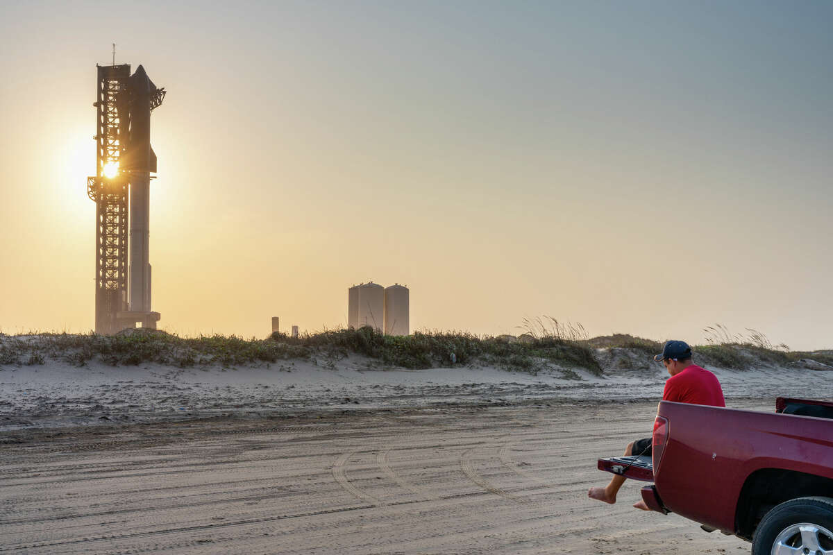 BROWNSVILLE, TEXAS - JUNE 05: A person sits out the back of their pickup truck as the sun sets behind the SpaceX Starship ahead of its fourth flight test at Boca Chica beach on June 05, 2024 in Brownsville, Texas. With each launch, and a focus of various objectives, the Starship remains the world's most powerful launch vehicle ever created. During the fourth flight test, SpaceX will continue its ongoing assessments with a focus on â€œdemonstrating the ability to return and reuse Starship and Super Heavy...' The company says that the 'primary objectives will be executing a landing burn and soft splashdown in the Gulf of Mexico with the Super Heavy booster, and achieving a controlled entry of Starship,â€ according to a news release. (Photo by Brandon Bell/Getty Images)