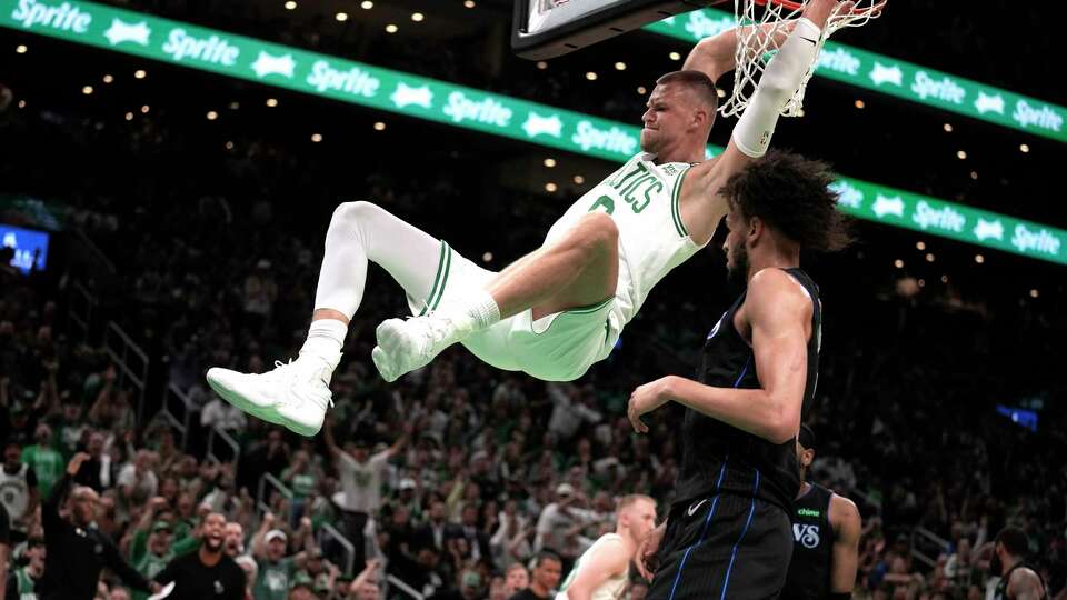 Boston Celtics center Kristaps Porzingis dunks next to Dallas Mavericks center Dereck Lively II, foreground, during the first half of Game 1 of basketball's NBA Finals on Thursday, June 6, 2024, in Boston.