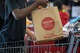 A customer puts a bag of food items into a shopping cart after purchasing them at Grocery Outlet in Oakland, Calif., on June 7, 2024.