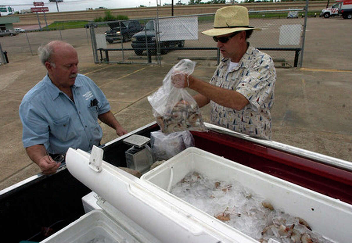 Port Bolivar Seafood owner Gary Oliveira, right, weighs out a 5 lb bag of fresh shrimp out of the coolers for Howard Hassler, owner of the Trailer Hitch Depot in Beaumont. Dave Ryan/The Enterprise