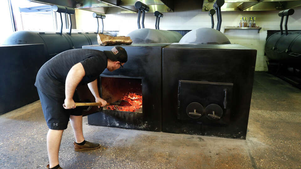 In this photo from May 2019, pit crew member Fletcher Sheridan stokes the fires in one of the pits at Truth BBQ, a barbecue joint on Washington Avenue in Houston.