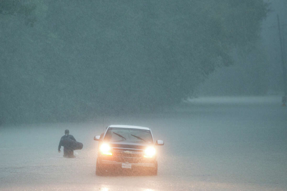 A man walks into high water into his neighborhood as rain from Tropical Depression Imelda inundated the area on Thursday, Sept. 19, 2019, near Patton Village, Texas.