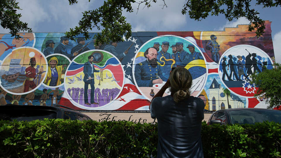 A visitor takes a photograph of the Absolute Equality Mural, which was unvailed last Juneteenth, with his cellphone, Wednesday, June 15, 2022, in Galveston, Texas. Galveston is the birthplace of Juneteenth, but has seen a steady decline in its Black population over the years. (Yi-Chin Lee/Houston Chronicle via AP)