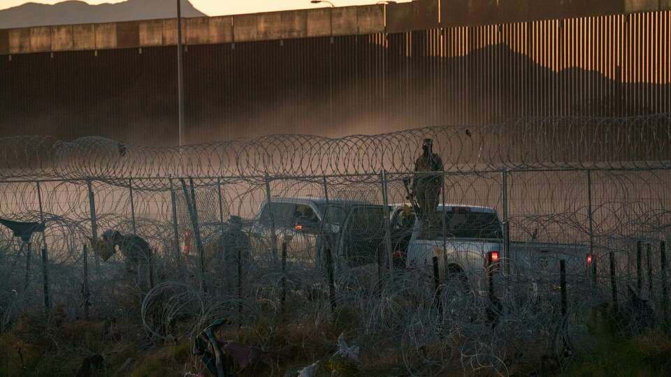 A Texas National Guard soldier holding a pepper ball launcher monitors the concertina wire along the border in El Paso that migrants must cross to surrender to Border Patrol in El Paso, on June 1, 2024.