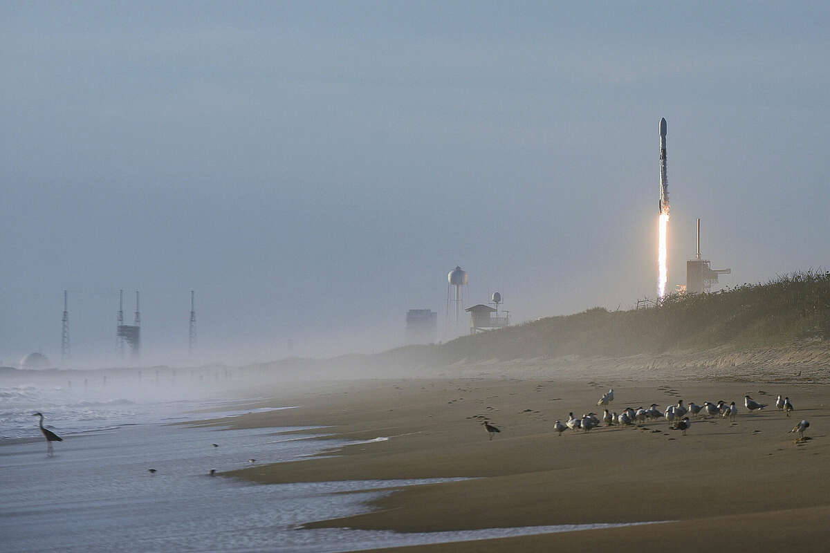 A SpaceX Falcon 9 rocket carrying 60 Starlink satellites forms a vapor cone after launching from pad 39A at the Kennedy Space Center in Florida as seen from Playalinda Beach at Canaveral National Seashore near Titusville, Florida on March 18, 2020.