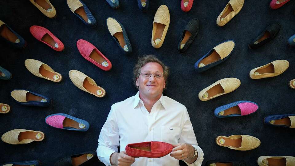 Marcus Spagnoletti poses for a photo with shoes from his line of shoes Tuesday, June 18, 2024, at his law firm in Houston. He uses a room at his law office to store and ship orders.