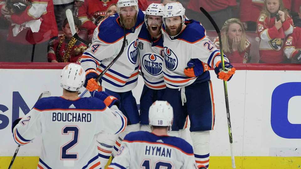 Edmonton Oilers players congratulate center Connor McDavid (97) after McDavid scored a goal during the third period of Game 5 of the NHL hockey Stanley Cup Finals against the Florida Panthers, Tuesday, June 18, 2024, in Sunrise, Fla. The Oilers defeated the Panthers 5-3.