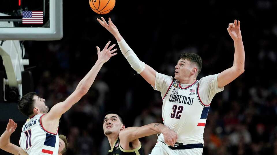 FILE - UConn center Donovan Clingan (32) reaches for the ball as Purdue center Zach Edey defends during the second half of the NCAA college Final Four championship basketball game, Monday, April 8, 2024, in Glendale, Ariz. Clingan is considered to be among the top prospects in this month's NBA draft. (AP Photo/Brynn Anderson, File)
