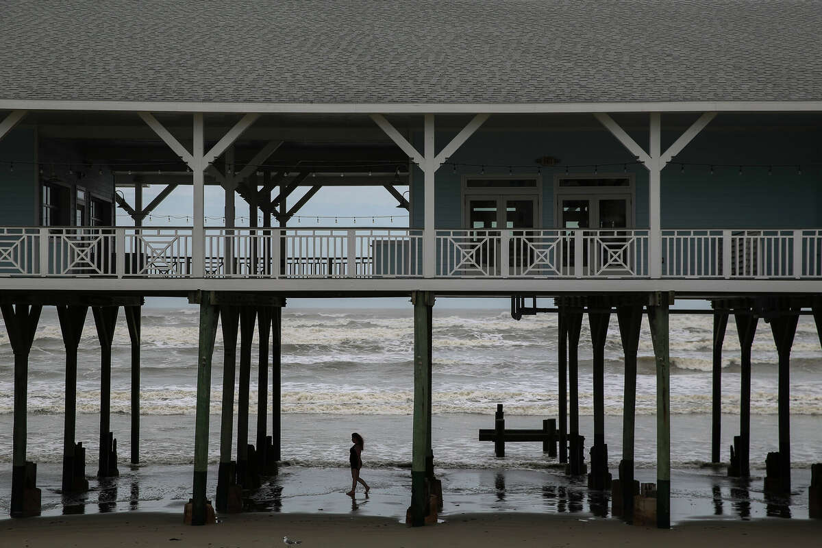 GALVESTON, TX - AUGUST 26: A woman walks on the beach as waves from Hurricane Laura roll in on August 26, 2020 in Galveston, Texas. Laura rapidly strengthened to a Category 4 hurricane during the day, prompting the National Hurricane Center to describe the accompanying storm surge as 'unsurvivable' and noted that it could penetrate up to 30 miles inland from the immediate coastline. (Photo by Thomas B. Shea/Getty Images)