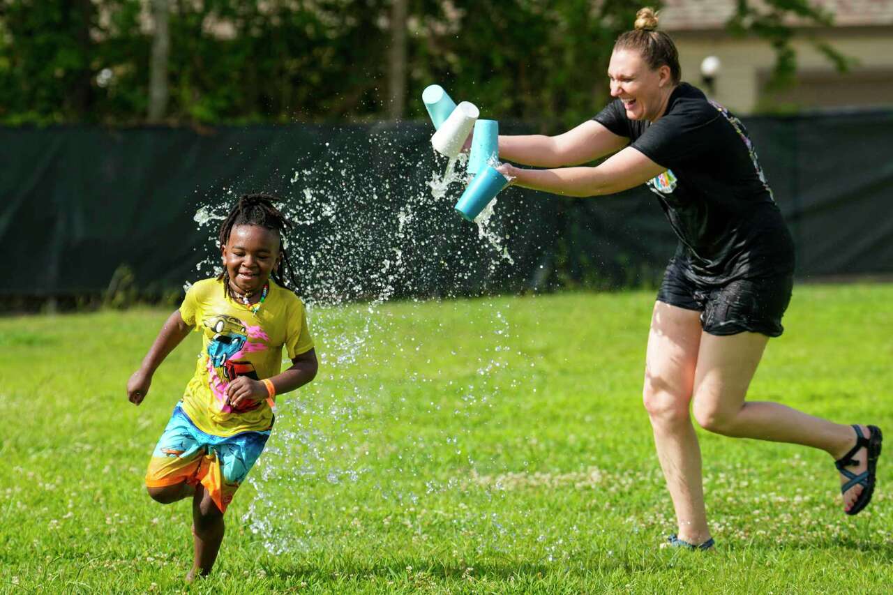 Katie O'Dell chases after a camper named Roger with cups of water during 