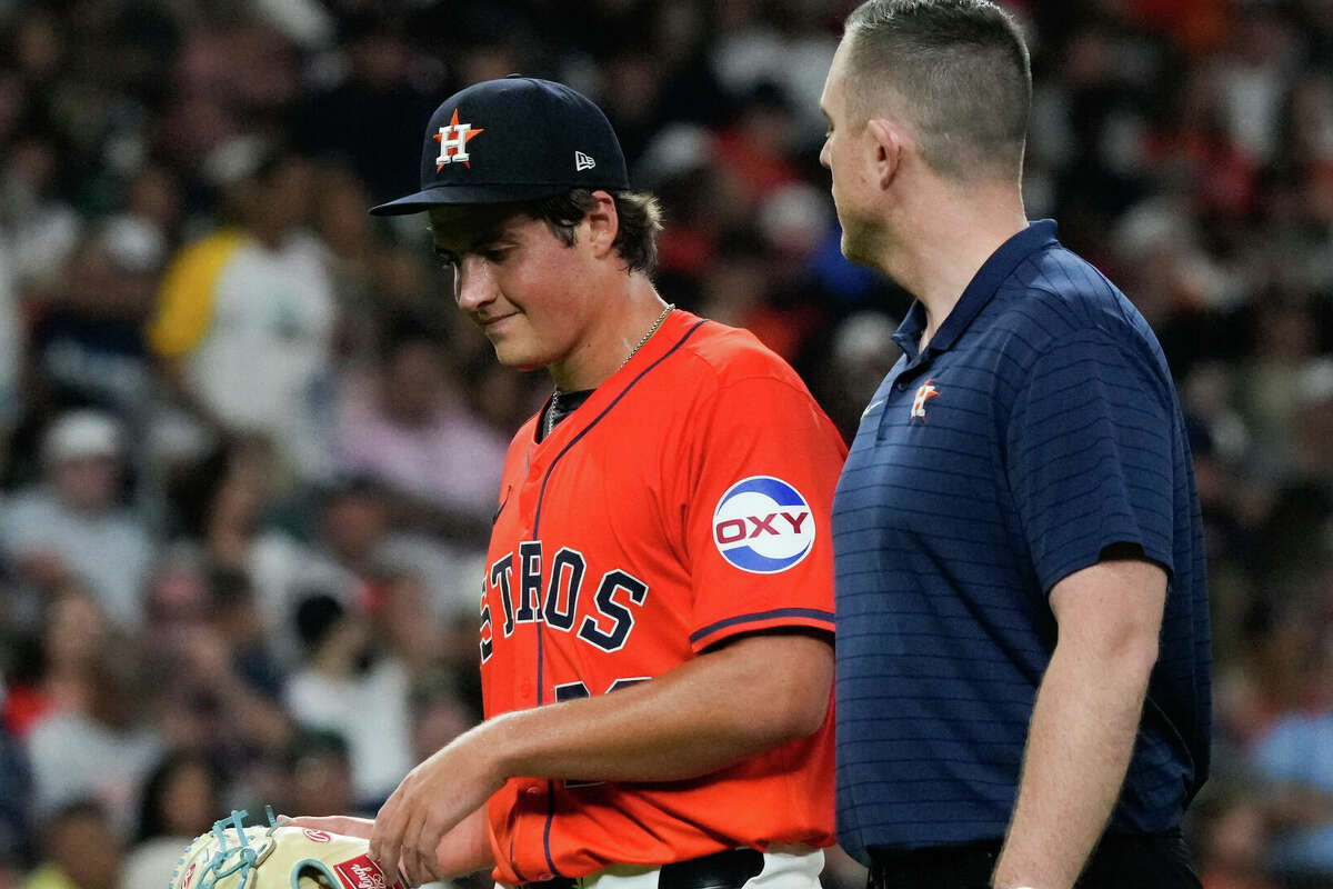 Houston Astros starting pitcher Jake Bloss (30) walks with a trainer back toward the dugout after three and two-thirds innings during an MLB baseball game at Minute Maid Park, Friday, June 21, 2024, in Houston.