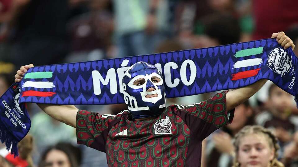 HOUSTON, TEXAS - JUNE 22: A fan of Mexico wearing a fighter mask holds a scarf of his team during the CONMEBOL Copa America 2024 Group B match between Mexico and Jamaica at NRG Stadium on June 22, 2024 in Houston, Texas.