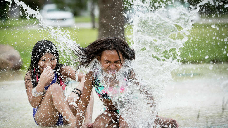 Emma Cordoba, 7, left, and Dallas Castillo, 6, play in the splash pad at Montie Beach Park in this photo taken on July 21, 2021, in Houston. Their mother, Karla Castillo, had said the kids were running around the house and needed to get out, so she loaded them in her car and brought them out to play in the water.