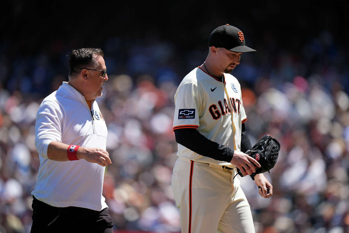 Blake Snell #7 of the San Francisco Giants heads off the field with member of the medical staff Dave Groeschner at Oracle Park on June 2, 2024 in San Francisco.