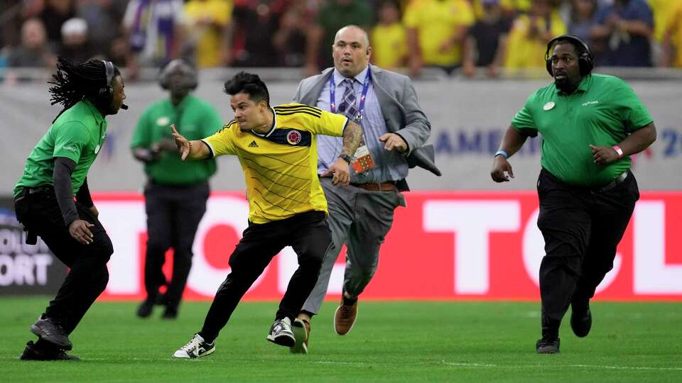 A pitch invader attempts to evade security guards at the end of a Copa America Group D soccer match between Colombia and Paraguay in Houston, Monday, June 24, 2024.