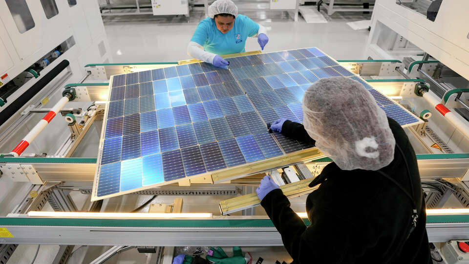 Monica Muñoz, top, and Denise Denning place polyethylene patches on solar panels at Elin Energy's solar panel manufacturing facility.