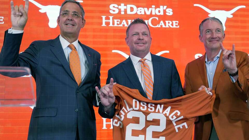 Jim Schlossnagle, center, stands with Texas Athletic Director Chris Del Conte, left, and Texas president Jay Hartzell, right, after he was introduced as the new NCAA college head baseball coach at Texas, Wednesday, June 26, 2024, in Austin, Texas. Schlossnagle left rival program Texas A&M. (AP Photo/Eric Gay)