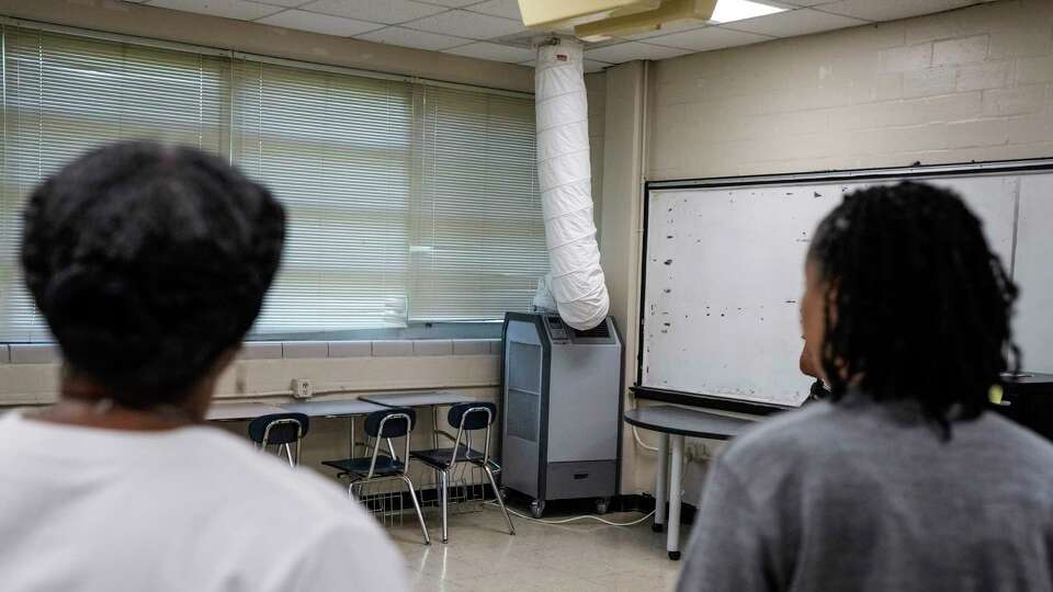 Principal Shundra Harris-Mosley, left, Inge Garibaldi, executive director feeders, take a look at a spot cooler in a classroom at Key Middle School on Wednesday, June 26, 2024 in Houston. School leaders showed some of the infrastructure problems in their buildings that would be addressed in a likely vote on the Houston ISD school bond in November.