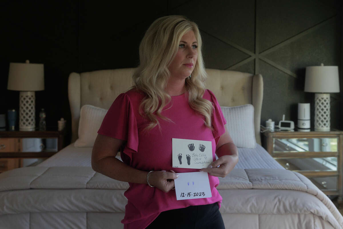 Hollie Cunningham poses for a portrait with the handprints and footprints of her daughters, who were both diagnosed with the same rare, fetal birth defect within the same year, at her home in Celina, TX, on Thursday, June 13, 2024. Cunningham had to leave the state twice in order to access abortions, now bearing the grief of losing her babies and trauma of having to flee the state.