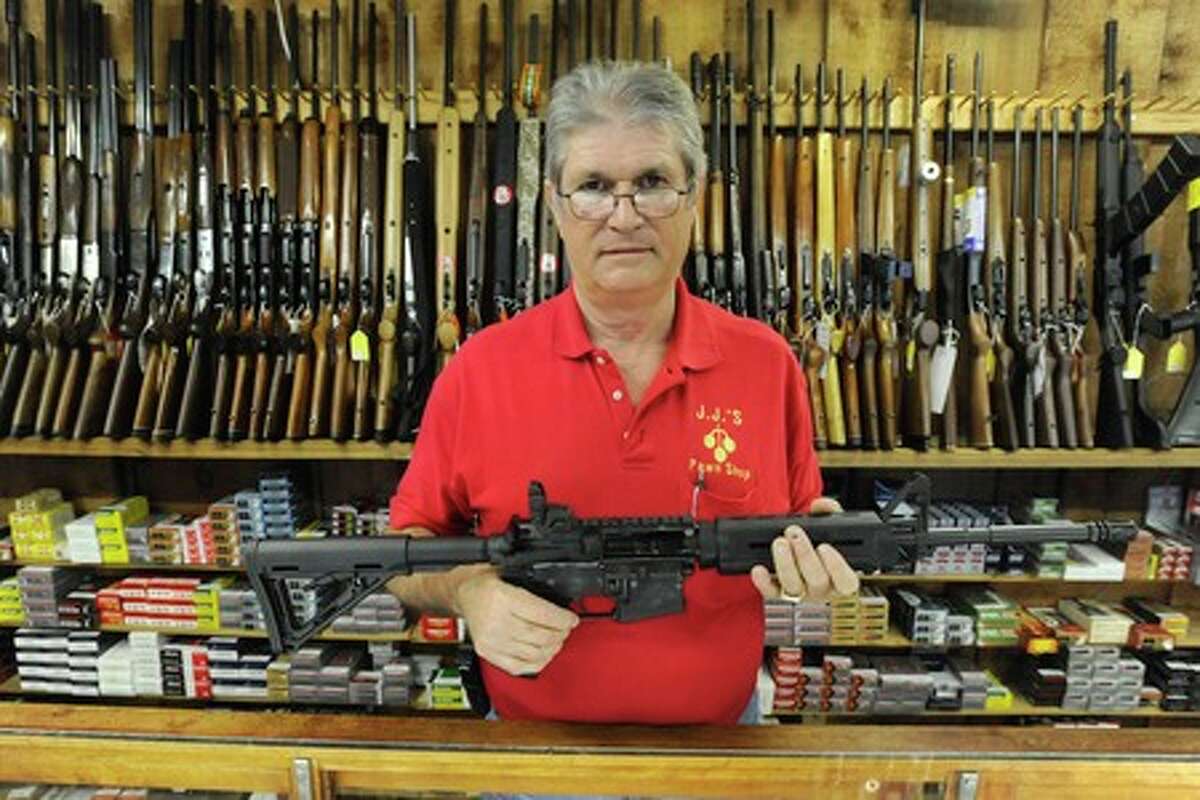 Jim Hedrick, owner of JJ's Pawn Shop, holds the popular selling Smith and Wesson M & P 15. Hendrick says, "If I had fifty of these, I could sell them in a day." Valentino Mauricio/The Enterprise