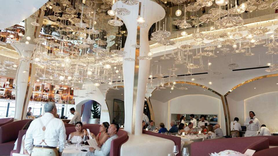 Patrons dine at Cocody, Friday, July 5, 2024, in Houston. The French restaurant features a neon-lavender glass wine wall and a blown-glass ceiling.