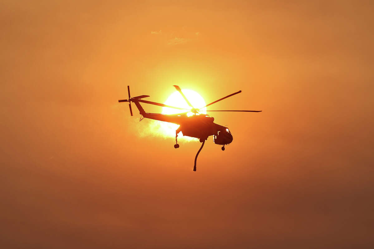 LOS OLIVOS, CALIFORNIA - JULY 06: A firefighting helicopter flies as the Lake Fire burns in Los Padres National Forest with evacuation warnings in the area on July 6, 2024 near Los Olivos, California. The wildfire in Santa Barbara County has scorched over 13,000 acres amid a long-duration heat wave which is impacting much of California.